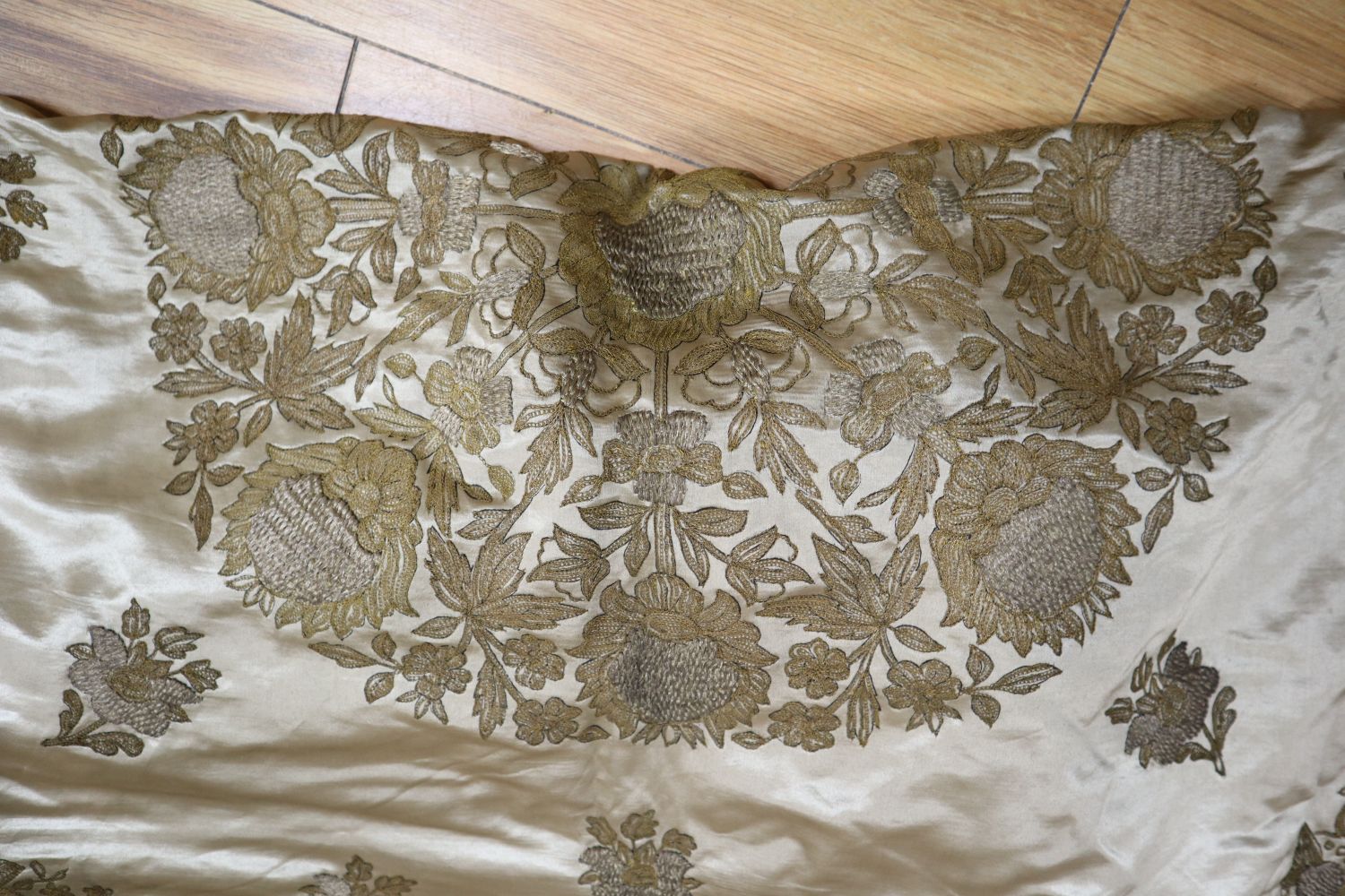 A silk bed cover, heavily embroidered in gold and silver coloured threads, silk lined in pale blue silk, 126 x 120cm